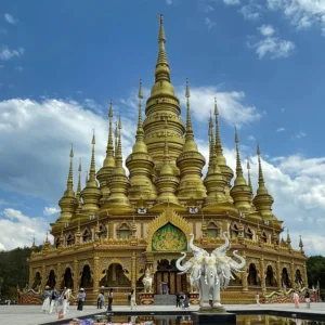在 勐泐大佛寺,金碧輝煌的佛塔群層層疊起,白象雕塑佇立前方,建築融合南傳佛教風格,氣勢宏偉莊嚴。