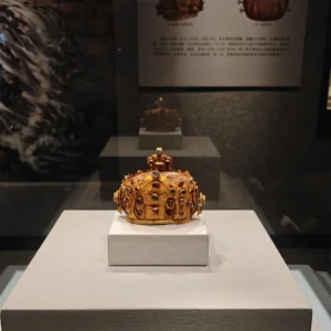 在 雲南國家寶藏館 展廳中,一頂鑲嵌紅藍寶石的金冠陳列於玻璃展櫃內,在燈光映照下展現出華麗質感與濃厚歷史氛圍。