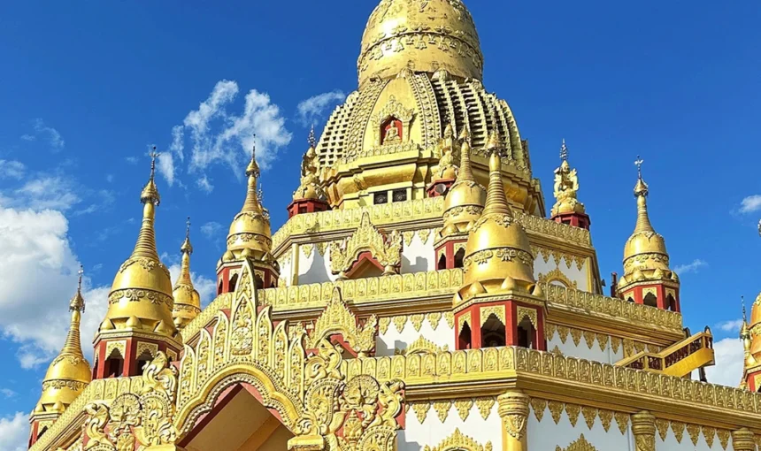 中國雲南芒市勐煥大金塔,宏偉鍍金佛塔,精緻雕刻與聳立尖塔,背景是澄澈藍天。