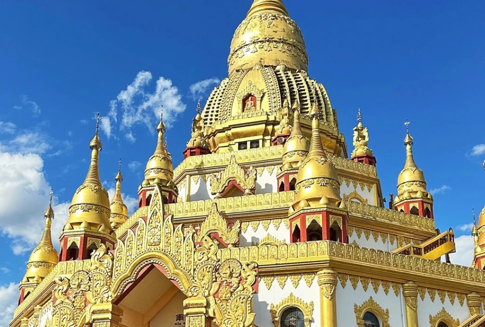 中國雲南芒市勐煥大金塔，宏偉鍍金佛塔，精緻雕刻與聳立尖塔，背景是澄澈藍天。