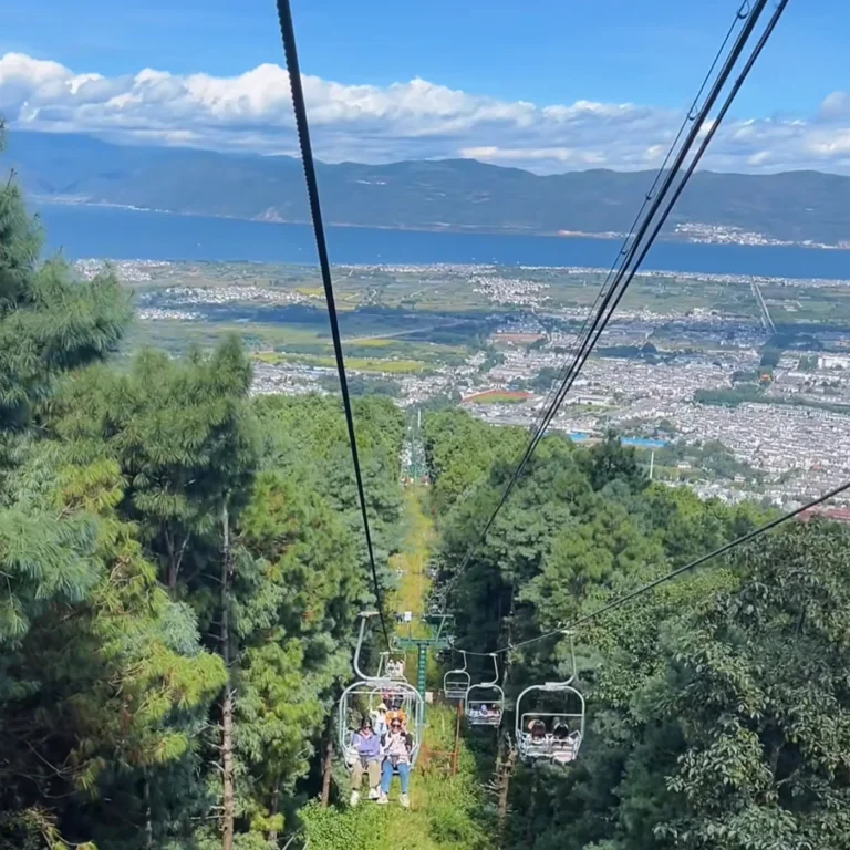 大理蒼山索道景觀,遊客搭乘纜車穿越森林山坡,俯瞰洱海與城市風光。
