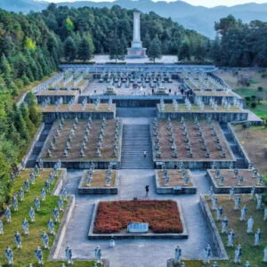 國殤墓園俯瞰景觀，整齊排列的士兵雕像與階梯式紀念廣場延伸至中央紀念碑，四周群山與松林環繞，象徵對滇西抗戰英烈的追思與敬意，是騰沖重要的歷史紀念與愛國教育場所。