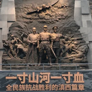 滇西抗戰紀念館大型歷史浮雕雕塑，呈現抗日戰爭時期軍民並肩作戰的場景，中央人物象徵指揮與守護家園的決心，上方飛機與戰士形象重現滇西戰場的激烈戰鬥與歷史記憶。