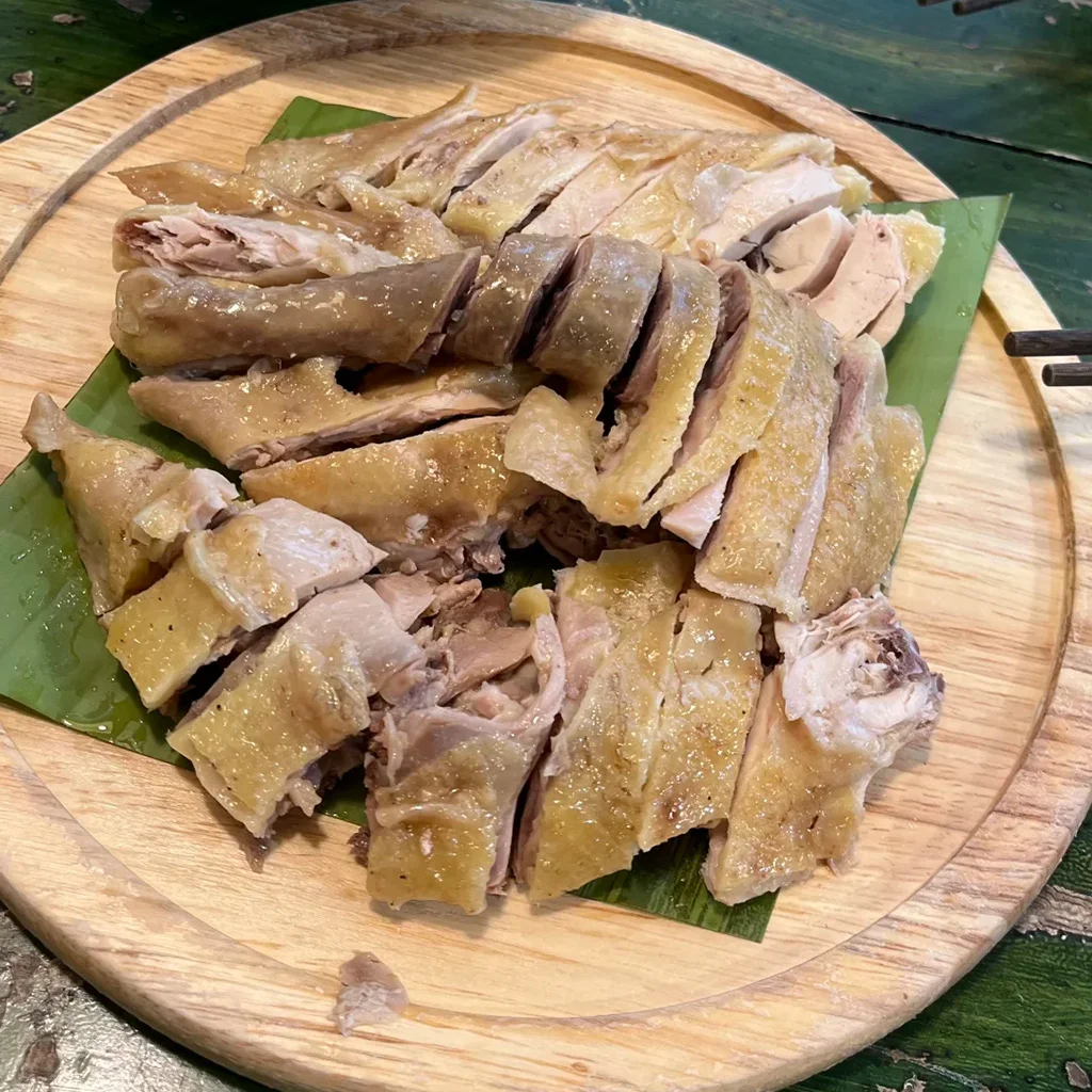 地道元陽哈尼蘸水雞,雲南特色料理。嫩白切雞切片盛於木盤,鋪上芭蕉葉,搭配香辣蘸水。