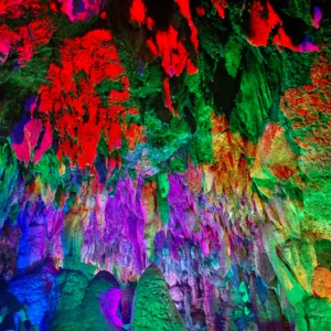石灰岩溶洞內巨大的鐘乳石與石筍,在霓虹紅、綠、紫色的燈光投射下顯得流光溢彩。