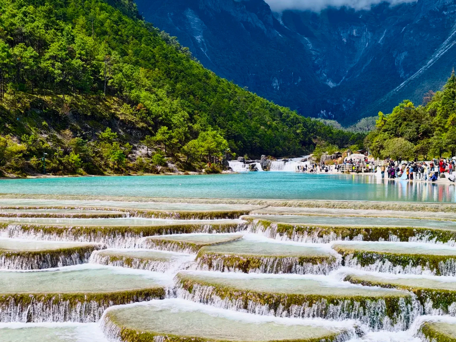 Lijiang Blue Moon Valley — Baishuitai 雲南麗江白水台,層層疊疊的鈣華階梯瀑布流淌著蒂芬妮藍湖水,兩側是蒼鬱山林,遠處環繞巍峨雪山,宛如人間仙境。