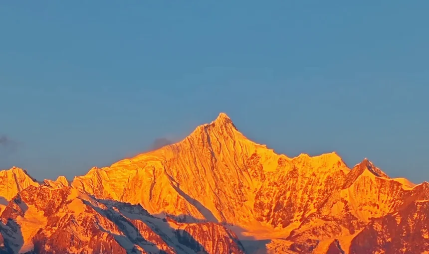 香格里拉梅里雪山日照金山絕景,朝陽金光浸染萬年雪域主峰,無人登頂藏地神山聖境,澄藍晴空下金頂輝煌燦爛、氣勢萬千。