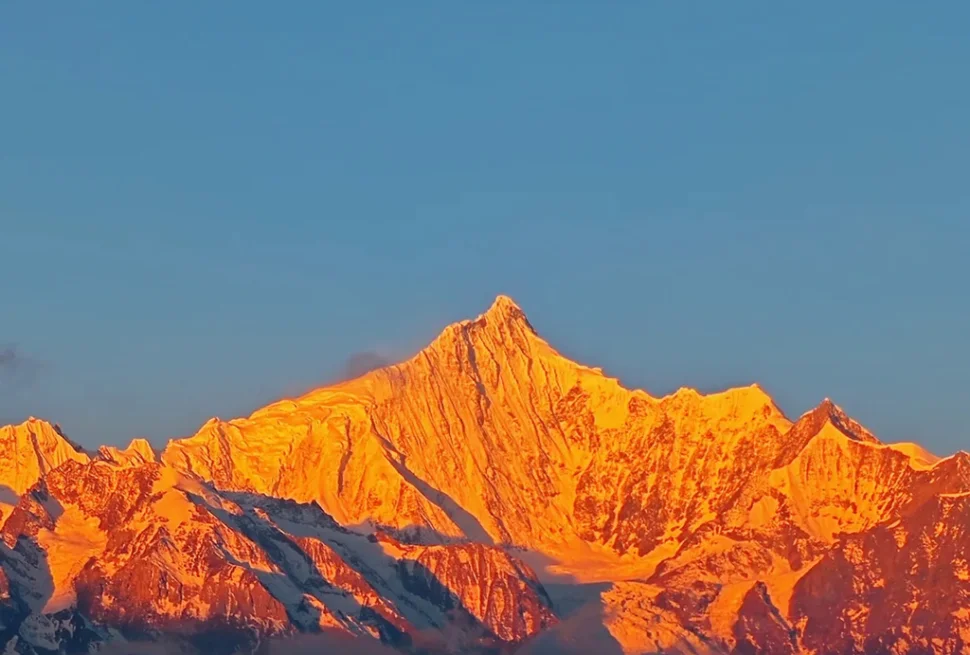 香格里拉梅里雪山日照金山絕景，朝陽金光浸染萬年雪域主峰，無人登頂藏地神山聖境，澄藍晴空下金頂輝煌燦爛、氣勢萬千。