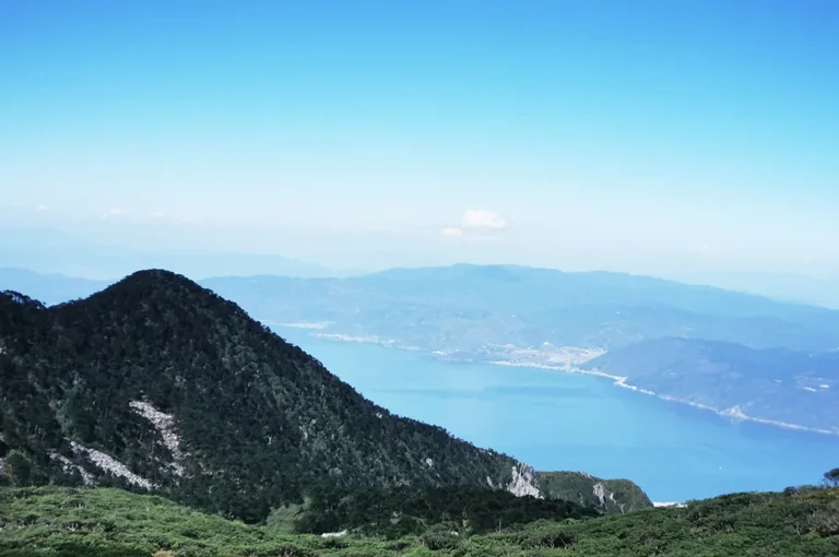 從蒼山俯瞰洱海，山峰與高山湖泊交織，遠方湖水蔚藍壯麗。