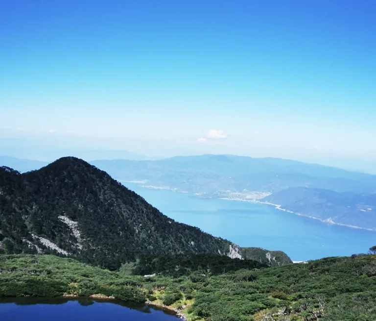 從蒼山俯瞰洱海，山峰與高山湖泊交織，遠方湖水蔚藍壯麗。