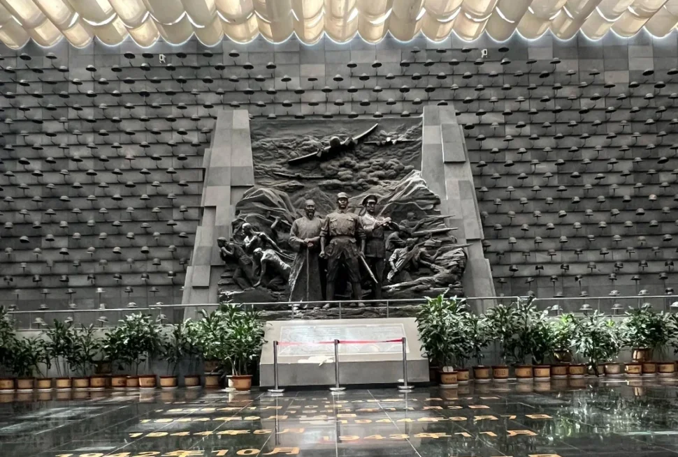 騰衝國殤墓園抗戰紀念館大廳，以中央雕塑與滿牆鋼盔為核心，再現滇西抗戰的崢嶸歲月，是對遠征軍將士的莊嚴致敬。