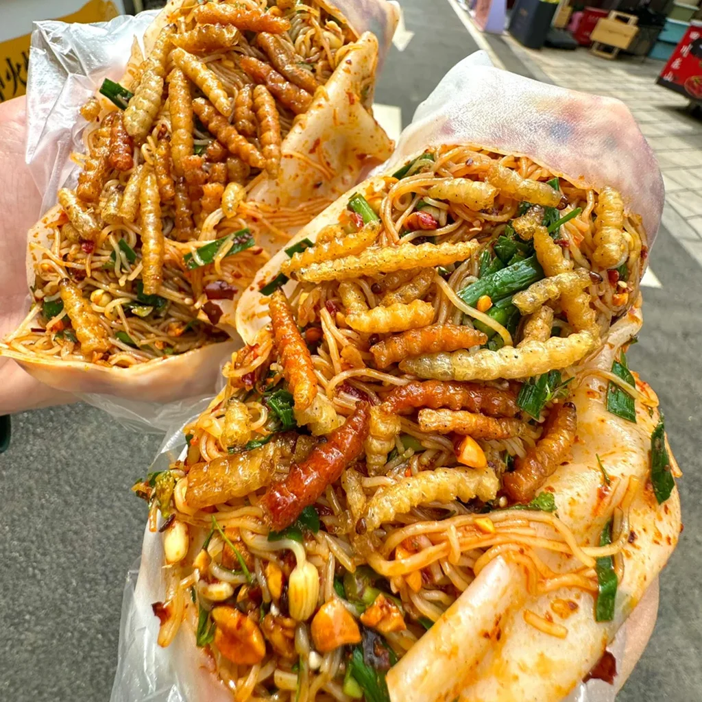 地道騰衝裹卷粉,雲南街頭美食特色。香辣米線搭配酥脆昆蟲幼蟲、韭菜、花生,包裹在薄米皮中。