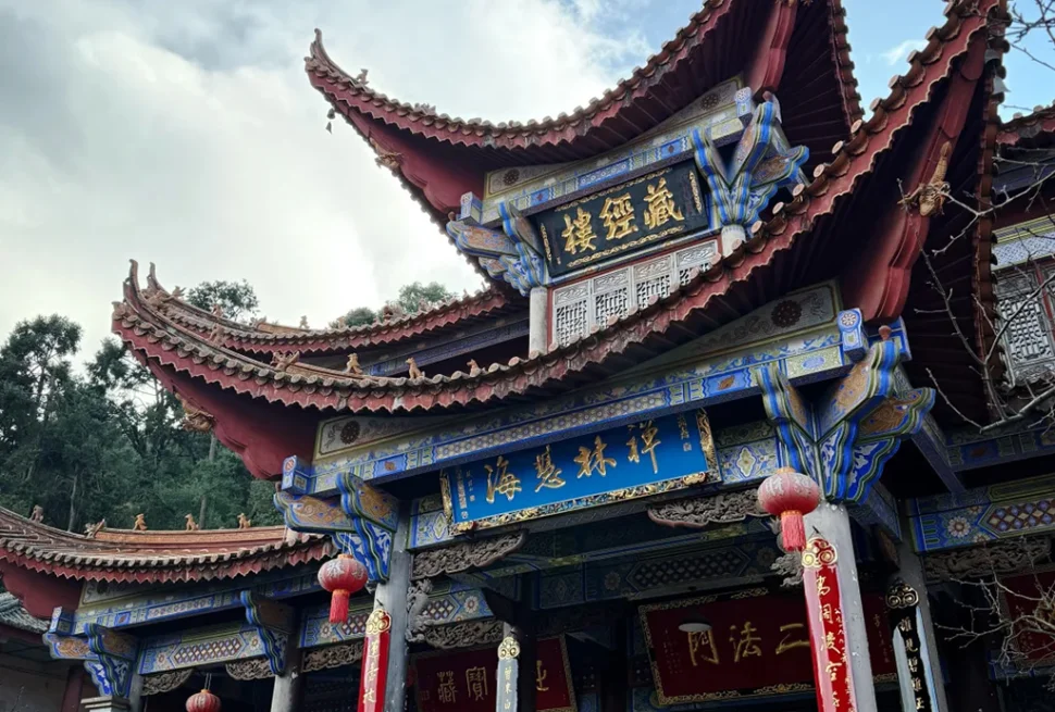 昆明西山華亭寺的藏經樓，飛檐翹角的傳統中式建築，彩繪樑柱與紅燈籠相映，是西山深處充滿禪意的古剎景點。