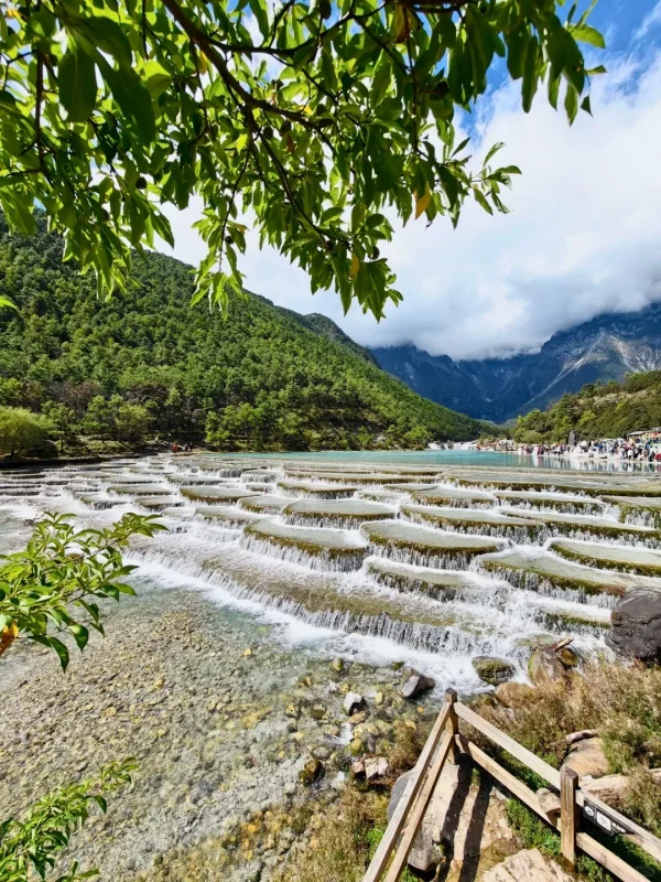 麗江藍月谷湖水清澈,森林與山脈在雲霧環繞下形成壯麗景觀。