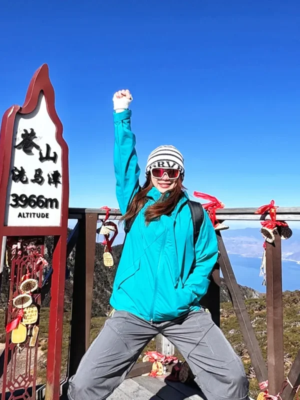 遊客在大理蒼山洗馬潭,站在海拔3966米標誌旁,俯瞰山巒與湖景。