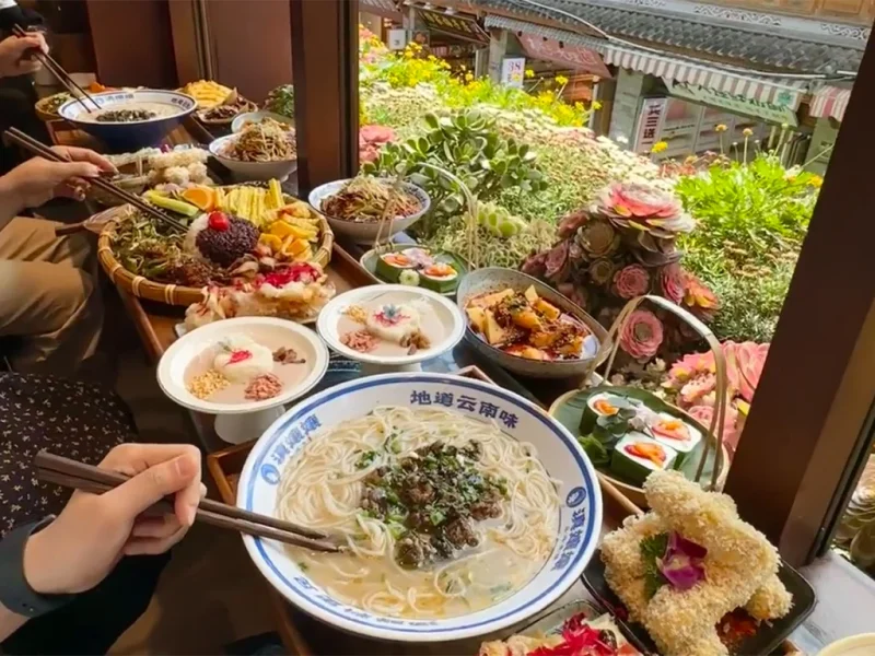 大理美食展示,包含雲南特色麵食、米飯料理與多樣在地佳餚,擺放於窗邊餐桌。