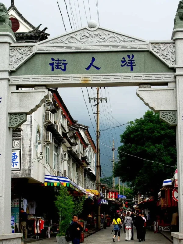 大理洋人街牌坊,傳統石雕門樓與街道景象,展現古城熱鬧氛圍。
