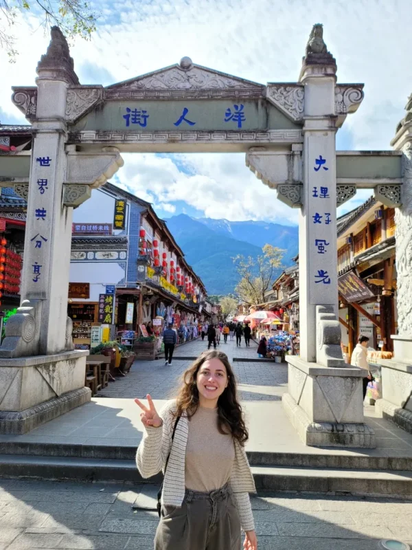 大理洋人街牌坊,傳統石門與熱鬧街景,遊客穿梭於古城之中。