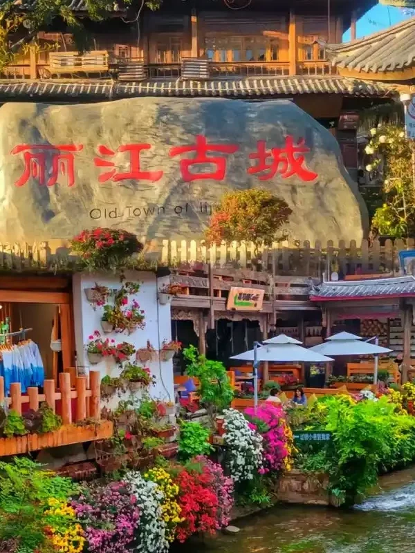 麗江古城著名的大水車景觀,巨大的木製水車在清澈河道旁緩緩轉動,周圍是傳統納西族建築與古城街景,遊客漫步其間,展現麗江古城融合歷史文化與自然水景的特色風光。