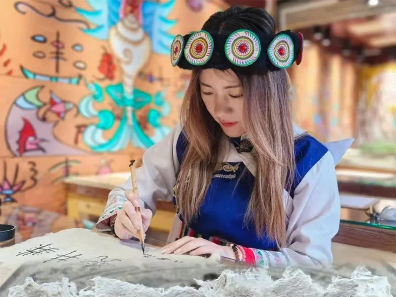 身穿納西服飾的遊客書寫東巴文字,體驗文化。