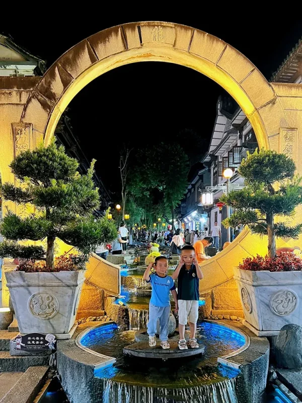 大理古城夜景,月亮門與流水景觀點亮夜晚,人們享受熱鬧街景。