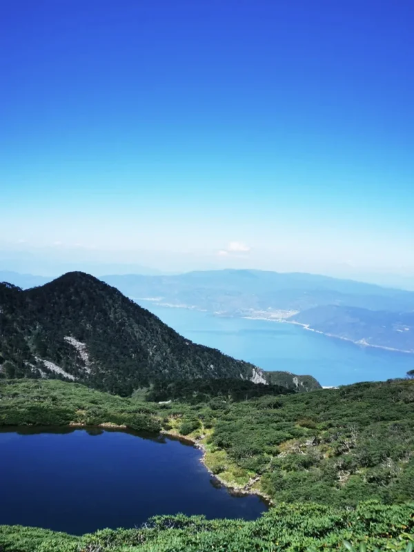 從蒼山俯瞰洱海,山峰與高山湖泊交織,遠方湖水蔚藍壯麗。