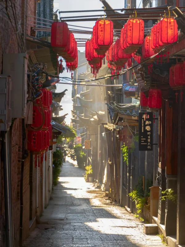 大理雙廊古鎮巷道,紅燈籠與傳統建築交織,陽光灑落溫暖街景。