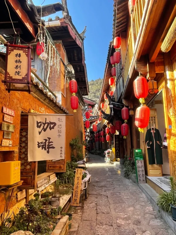 束河古鎮的陽光古巷,紅燈籠高掛、木質建築溫暖,藍天下的青石板路,是麗江最具慢生活氛圍的巷弄畫面。