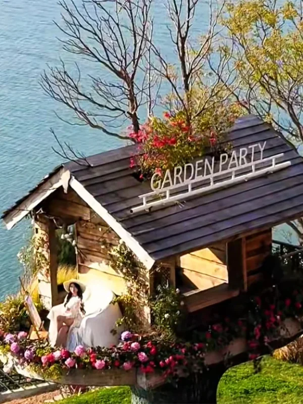 大理洱海小木屋慢生活場景,湖畔木屋環繞花卉,一人悠閒享受寧靜時光。