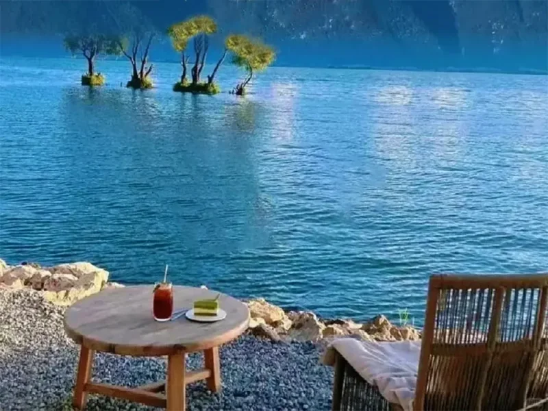 大理洱海邊慢生活場景,湖畔桌椅與飲品,遠望平靜湖水與樹影。