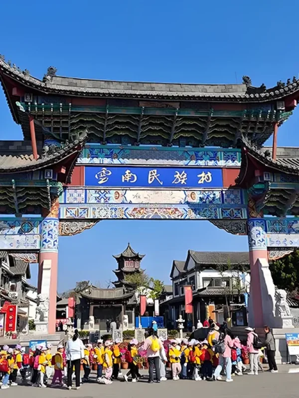 雲南民族村入口牌樓,傳統建築與遊客活動交織,展現文化氛圍。
